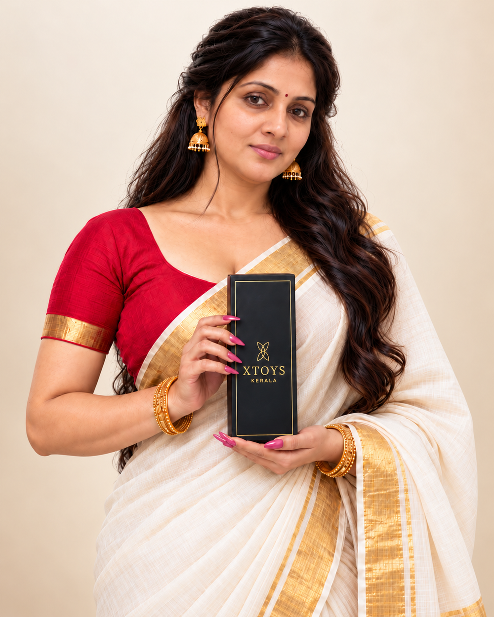 Xtoys Kerala model in a Kerala sari holding a black Xtoys Kerala box against a warm cream and champagne background